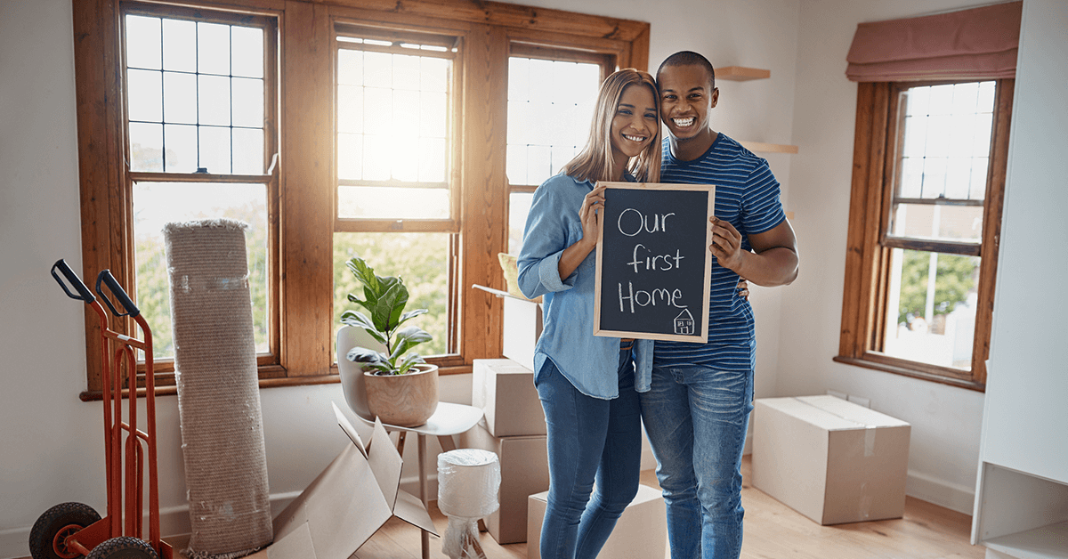 young African American couple holding a sign that reads our first home